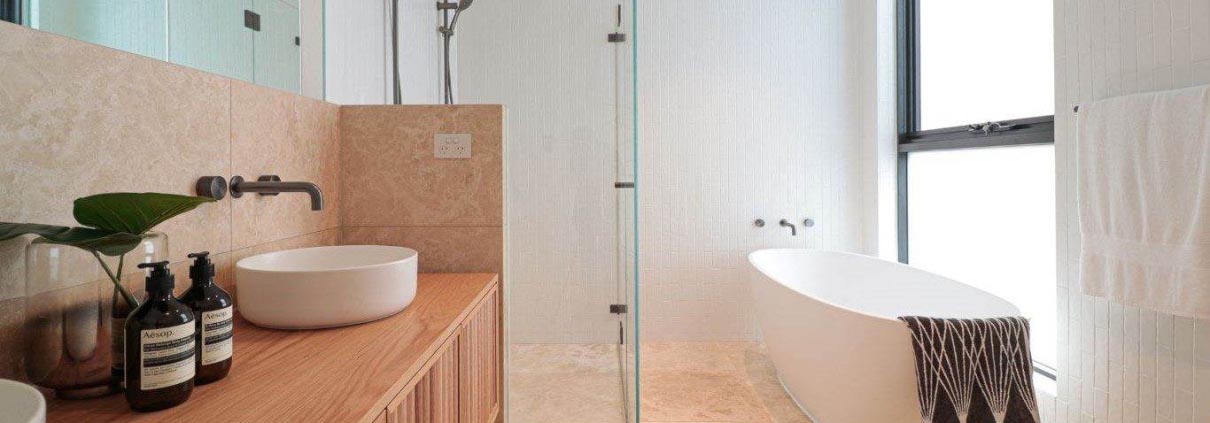 bathroom displaying bathtub, shower and sink with beige tiles