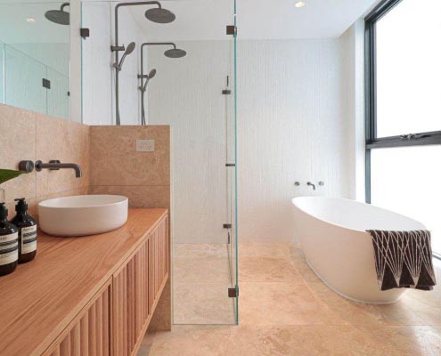 bathroom displaying bathtub, shower and sink with beige tiles
